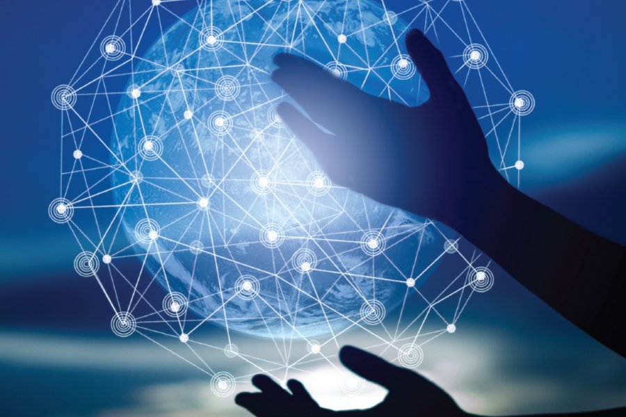 A pair of hands reaching toward a glowing digital globe surrounded by an interconnected web of nodes and lines. The image symbolizes global connectivity, networks, and digital integration, emphasizing themes such as technology, innovation, and worldwide collaboration in the digital era. The blue gradient background adds a futuristic and dynamic feel.