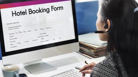 Travel agent looking at an online hotel booking form.