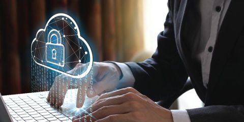 A professional working on a laptop with a holographic cloud icon featuring a locked padlock, symbolizing cloud security and data protection. The digital overlay includes binary code cascading down, emphasizing cybersecurity and the safeguarding of sensitive information in the digital cloud.
