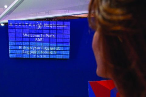 Woman staring at an airlines arrivals board.