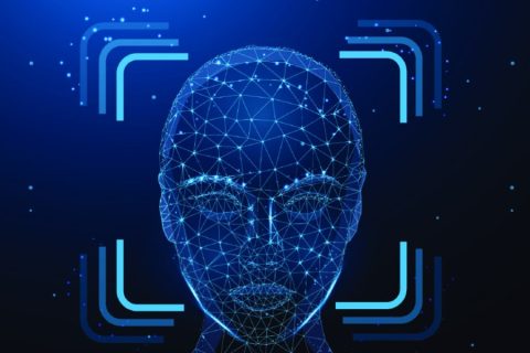 A futuristic digital representation of a human face constructed from interconnected glowing blue lines and nodes, resembling a wireframe. The face is framed by scanning brackets, suggesting facial recognition technology or biometric identification. The background is dark blue with scattered light particles, emphasizing a high-tech, digital theme.