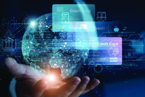 Fintech picture of a hand holding hologram of the earth and credit cards.