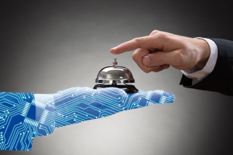 Man tapping a bell being held by a robot hand.