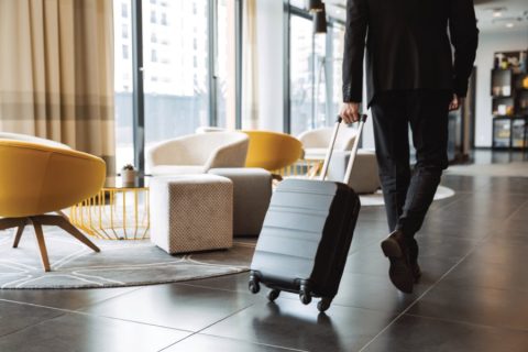 Man rolling a suitcase through a hotel.