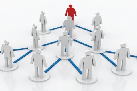 A network diagram featuring white, 3D human figures connected by blue lines on a white background. At the center-top stands a red figure, symbolizing leadership or central coordination. The connections illustrate a hierarchy or organized structure of communication, with each figure positioned on circular bases interconnected by blue pathways.