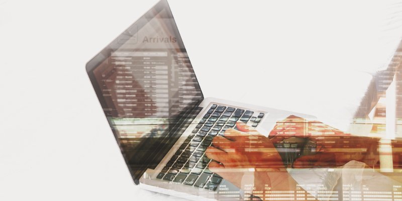 A laptop being used by a person, with a transparent overlay of an airport arrivals board, symbolizing travel management, booking, and real-time connectivity through technology.