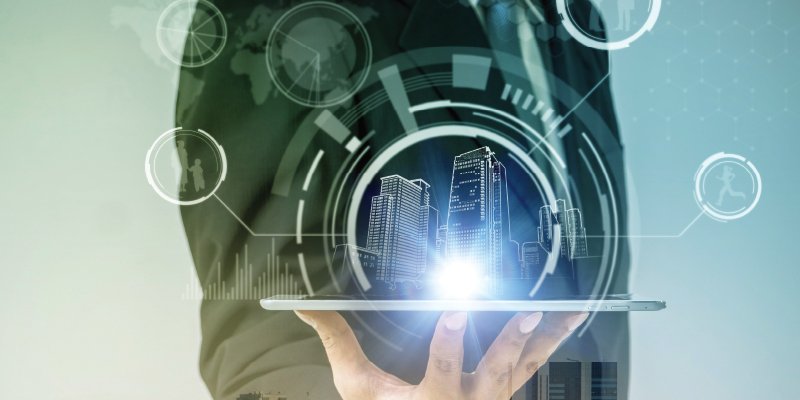 A business professional holding a tablet emitting a glowing projection of a futuristic cityscape. Overlaid are holographic circular diagrams, icons, and data visualizations, symbolizing smart technology, innovation, and urban development. The image conveys the integration of digital technology in urban planning and business strategies, with a sleek and futuristic aesthetic.