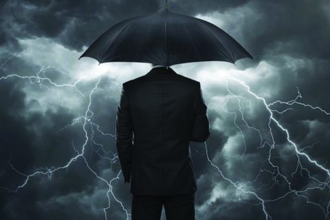 Man holding an umbrella in a storm.