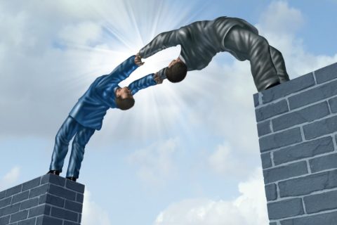 Two men bending over backwards to join their arms.