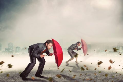 Two People walking against the wind with Umbrellas to shield them